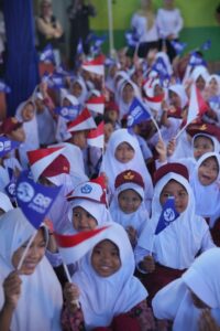 Siswa-siswi sekolah dasar antusias mengibarkan bendera Merah Putih dan bendera BRI Peduli pada peringatan Hari Anak Nasional 2026.